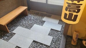 Une pièce avec un banc en bois, un tatami et un paravent en papier de riz.