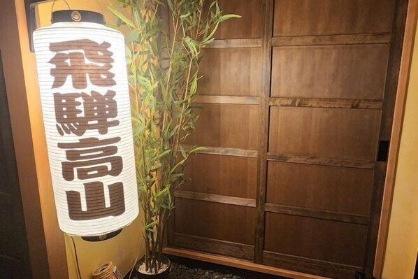 A traditional Japanese room with a sliding door, a bamboo plant, and a hanging lantern with Japanese characters.