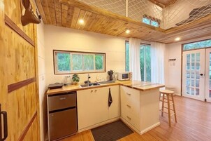 A compact kitchen with a refrigerator, microwave, sink, and wooden cabinets.