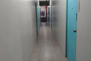 A corridor with teal doors, leading to a room with a visible door number. - Coco hotel (Paranaque)