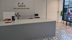 Un comptoir d’accueil avec une pancarte indiquant : « CoCo Coco Star Hotel MT Cor. »
