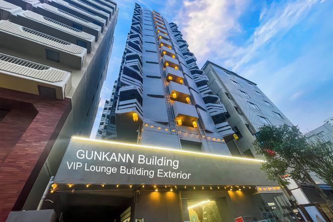 The exterior of the Gunkann Building, featuring a modern architectural design with multiple balconies and a prominent entrance.