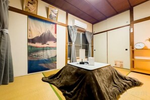 Ett traditionellt japanskt rum med tatamimattor på golvet, ett lågt bord med en duk, en målning av berget Fuji och en skjutdörr.