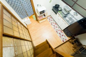 A kitchen with a microwave, sink, and stove. There is a wooden staircase leading to another level.