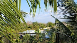 A view of a lush garden with palm trees and a metal railing. - farm sam sook (Lamphun)