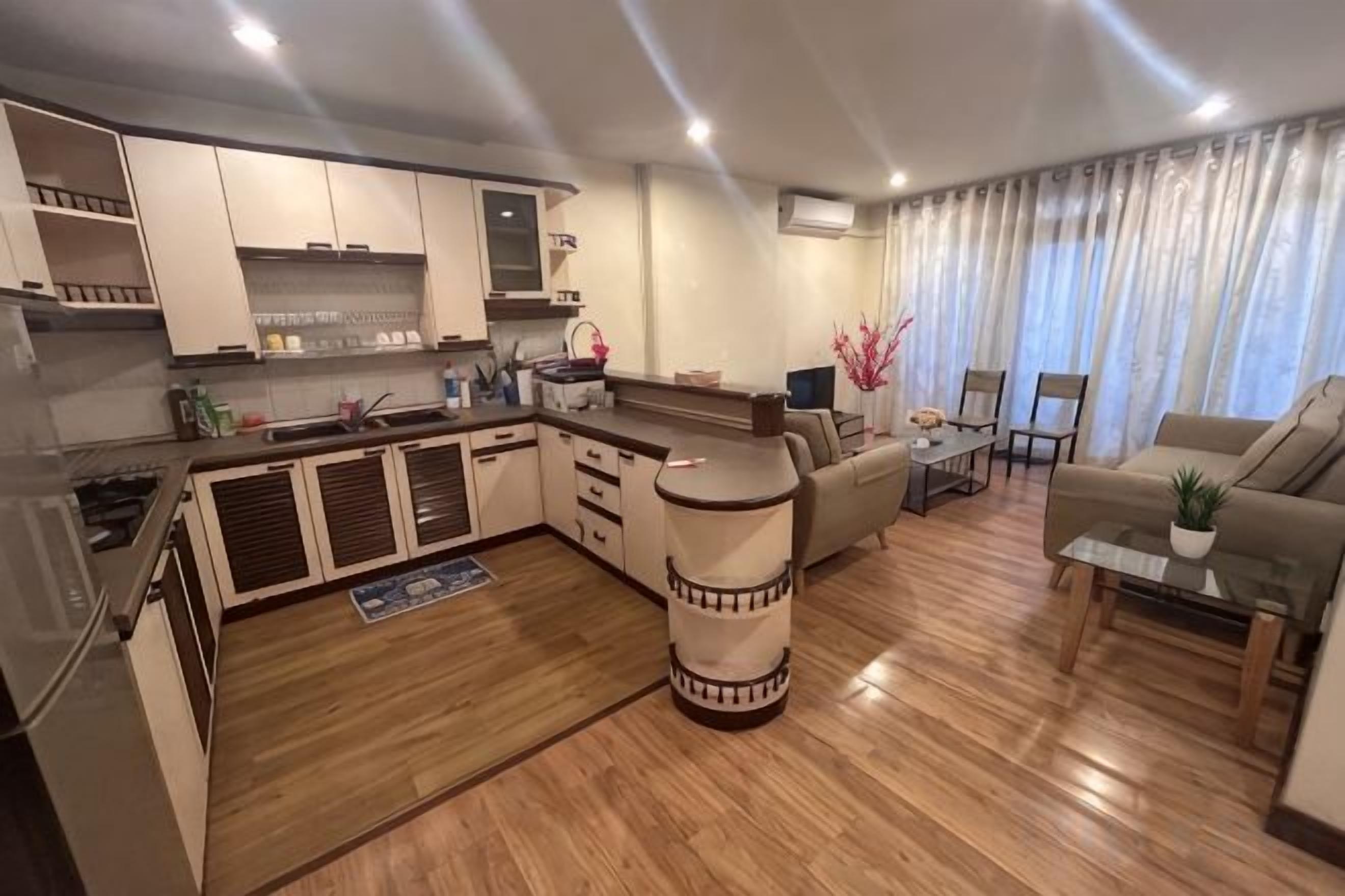 A modern kitchen with a central island, a dining area with a sofa and chairs, and a living room with a couch and a coffee table.