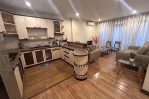 Una cucina moderna con isola centrale, zona pranzo con divano e sedie, e soggiorno con divano e tavolino.