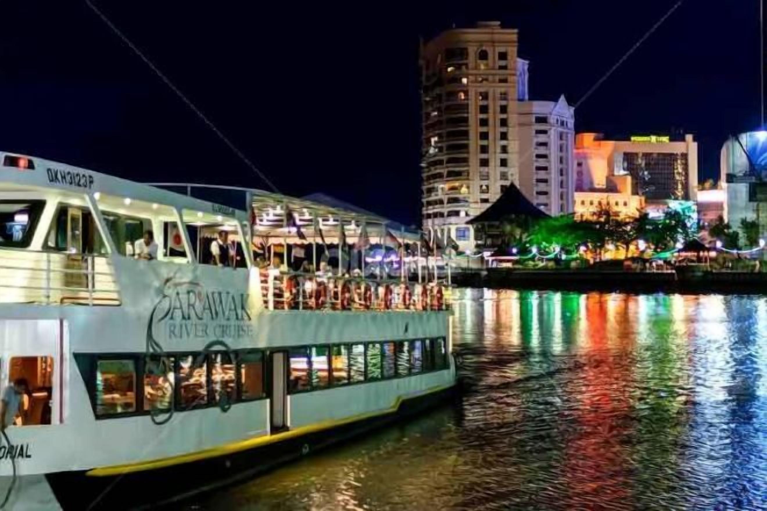 A river cruise boat with a dining area and a view of a city skyline at night.
