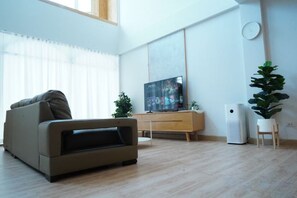 Ein modernes Wohnzimmer mit einer Couch, einem Flachbildfernseher, einer Pflanze und einem kleinen Tisch.