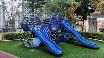 Une aire de jeux avec un toboggan bleu et des structures d’escalade.