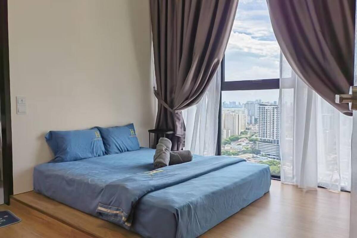 A bedroom with a bed, curtains, and a city view.