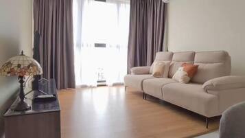 Un salon avec un canapé, une lampe et une vue par la fenêtre.