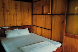 A wooden-paneled room with a bed, a headboard, and a window with a view. - Villa Pleiku City (Pleiku)