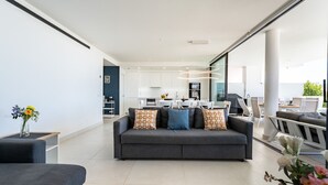 Ein modernes Wohnzimmer mit einem grauen Sofa, einem Couchtisch und einem Essbereich mit weißer Möbel.
