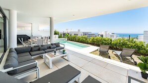 Ein moderner Außenbereich mit Pool, Sitzgelegenheit und Blick auf das Meer und die Skyline.