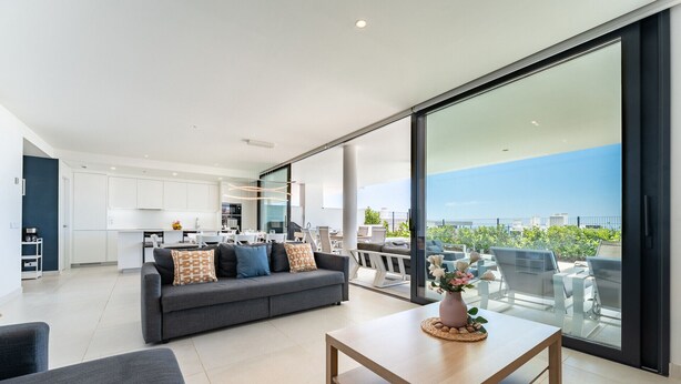 Ein modernes Wohnzimmer mit einer Couch, einem Couchtisch und einem Balkon mit Sitzgelegenheit im Freien.