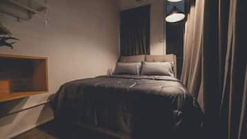 A bedroom with a bed, curtains, and a wall-mounted shelf.