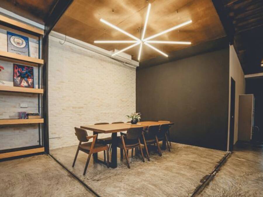 A room with a wooden table and chairs, a bookshelf, and a unique ceiling light fixture.