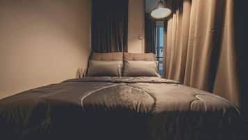 A bedroom with a bed, curtains, and a window.