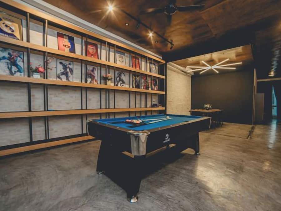A pool table in a room with wooden flooring and a wall of framed pictures.
