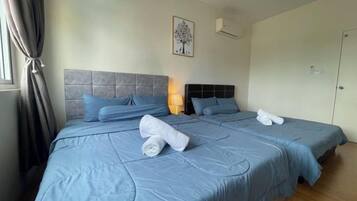 Een tweepersoonsbed met blauw beddengoed, een hoofdbord en een wandairconditioner.