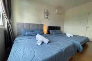A double bed with blue bedding, a headboard, and a wall-mounted air conditioner. - Comfy Homestay River View Kuching 4 pax (Kuching)