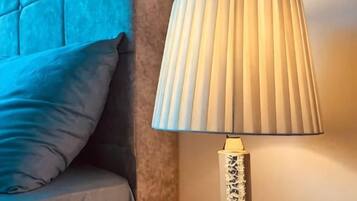 Een lamp met een plooilamp en een gestreept voetje, naast een kussen op een bank.