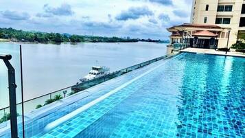 A swimming pool with a view of a river and a building in the background.