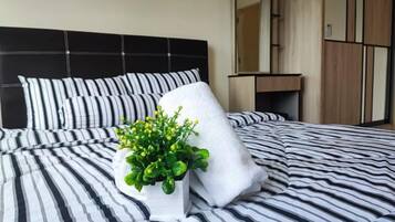 A bed with striped bedding, a white pillow, and a potted plant.