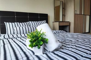 A bed with striped bedding, a white pillow, and a potted plant. - Comfy Homestay River View Kuching 4 pax (Kuching)