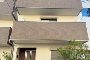 A multi-story residential building with balconies, a door, and a window. - Peace House｜4 Bedrooms, 5 Bathrooms, 5 Toilets, Parking & Terrace (Osaka)