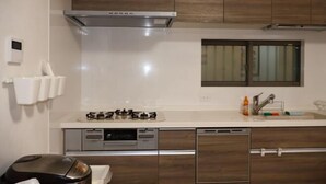 A modern kitchen with a stove, oven, and dishwasher, wooden cabinets, and a window.