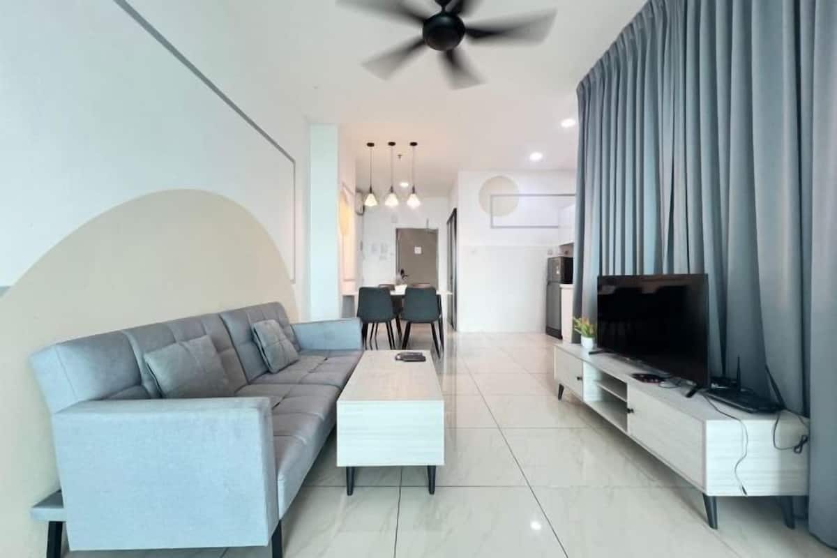 A modern living room with a sofa, coffee table, TV stand, ceiling fan, and dining area.