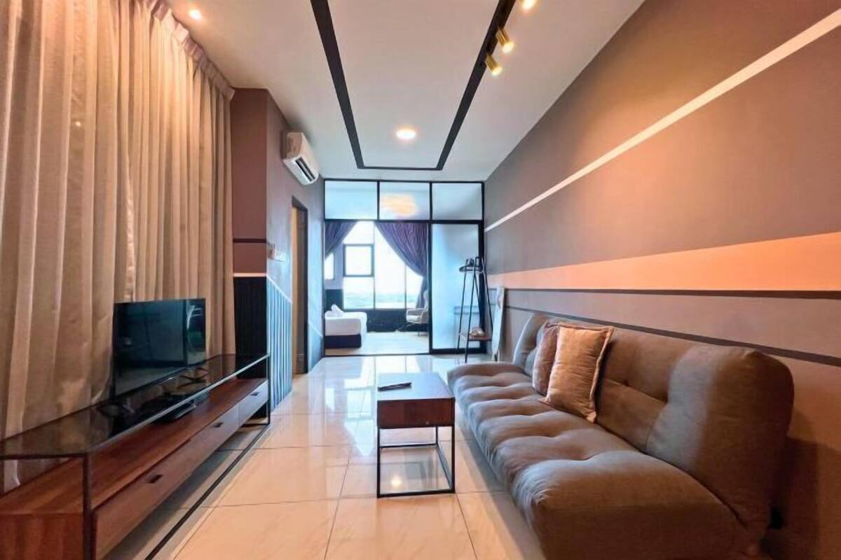 A modern living room with a flat-screen TV, a sofa, a coffee table, and a large window.