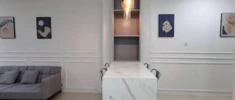 Una sala de estar moderna con una mesa de mármol, sofá gris y arte abstracto en la pared.