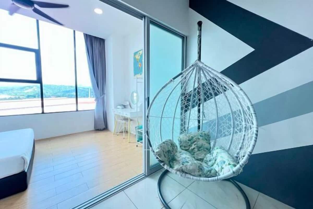 A room with a hanging chair, a bed, a desk, and a view of the outdoors.