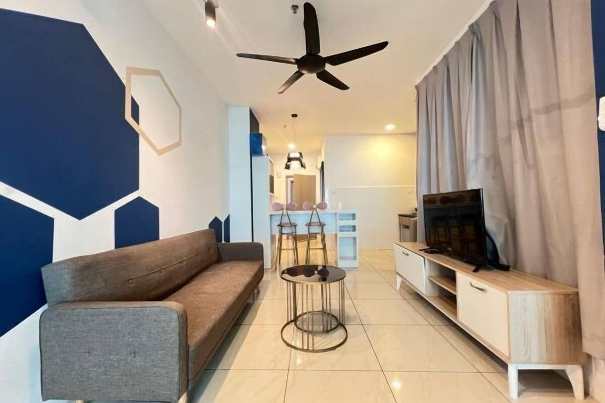 A modern living room with a sofa, a coffee table, a TV, and a ceiling fan.