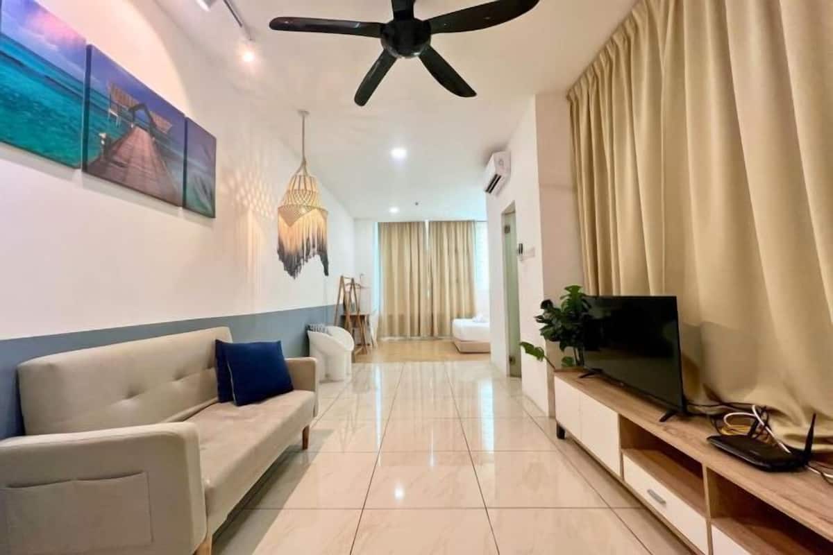 A modern living room with a sofa, TV, ceiling fan, artwork, and a plant.