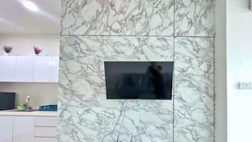 A modern kitchen with a marble backsplash, a built-in TV, and a countertop with a sink and some plants.
