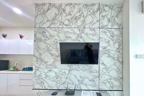 A modern kitchen with a marble backsplash, a built-in TV, and a countertop with a sink and some plants.