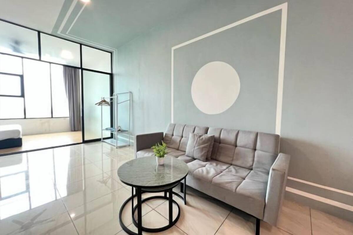 A modern living room with a grey sofa, a round table, and a large wall-mounted circular design.