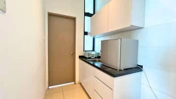 A narrow kitchen with white cabinets, a black countertop, and a refrigerator.