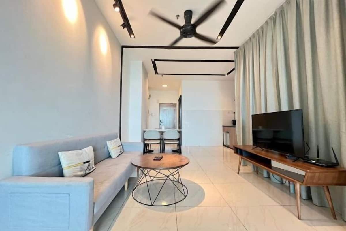 A modern living room with a sofa, a round coffee table, a TV, and a ceiling fan.