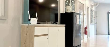 Una cocina moderna con televisión integrada, refrigerador y armario de madera.