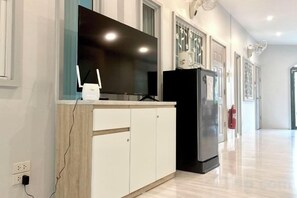 A modern kitchen with a built-in TV, a refrigerator, and a wooden cabinet. - Pimbunya house (Phibun Mangsahan)