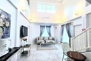 A modern living room with a sofa, TV, and artwork on the wall. - Pimbunya house (Phibun Mangsahan)