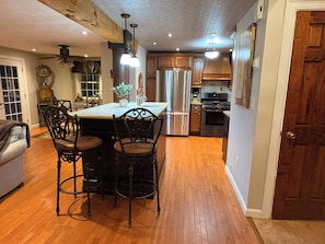 A kitchen with a central island, wooden cabinets, stainless steel appliances, and a dining area with a chandelier. - Spacious Townhouse l Retreat on Pawtuckaway River (Nottingham)