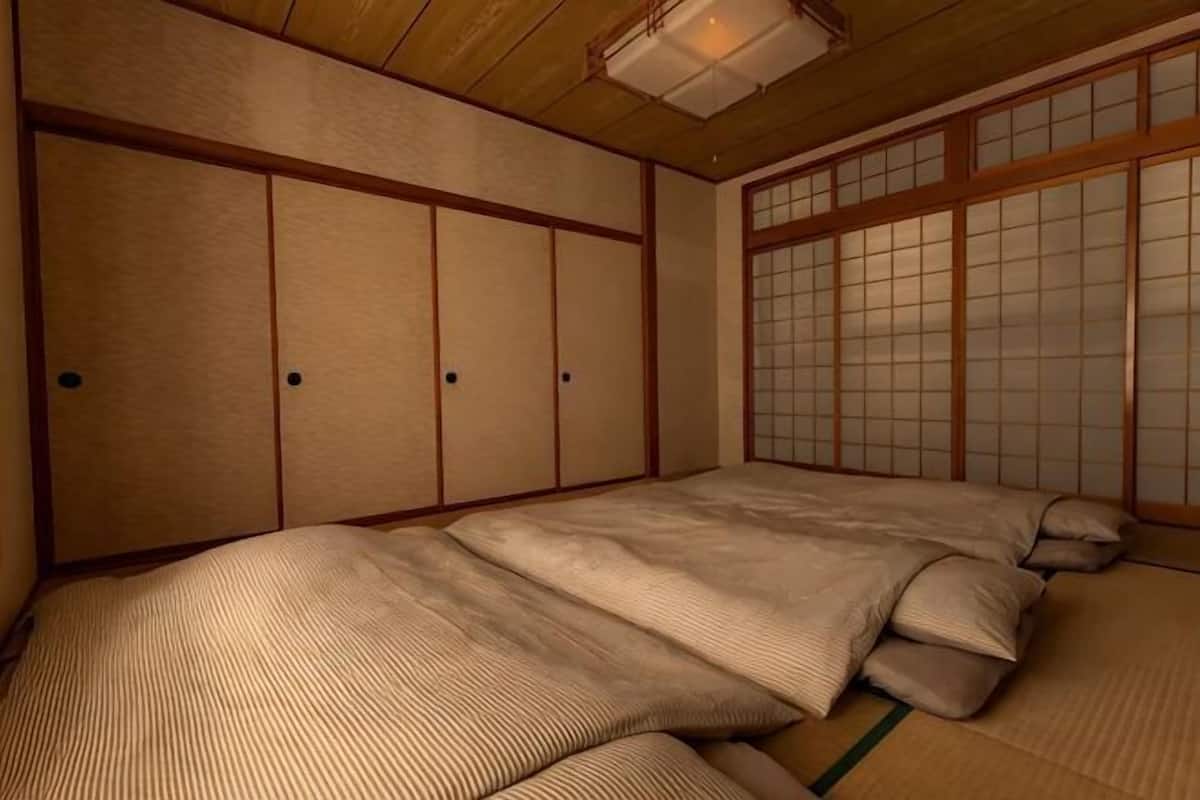 A traditional Japanese room with tatami flooring, shoji screens, and a futon bed.