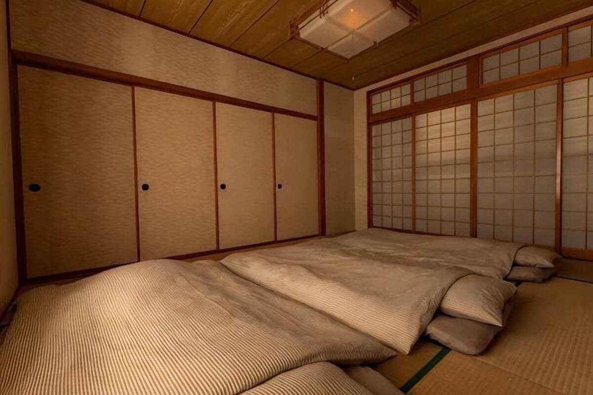 A traditional Japanese room with tatami flooring, shoji screens, and a futon bed.
