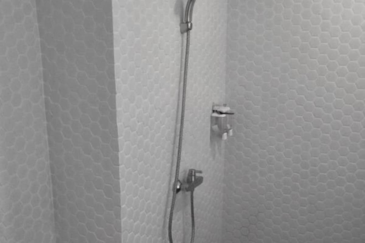 A shower with a hexagonal tile pattern on the walls and a metallic showerhead.